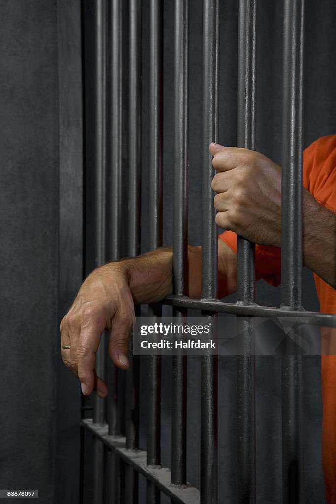 A prisoner standing behind his prison cell bars
