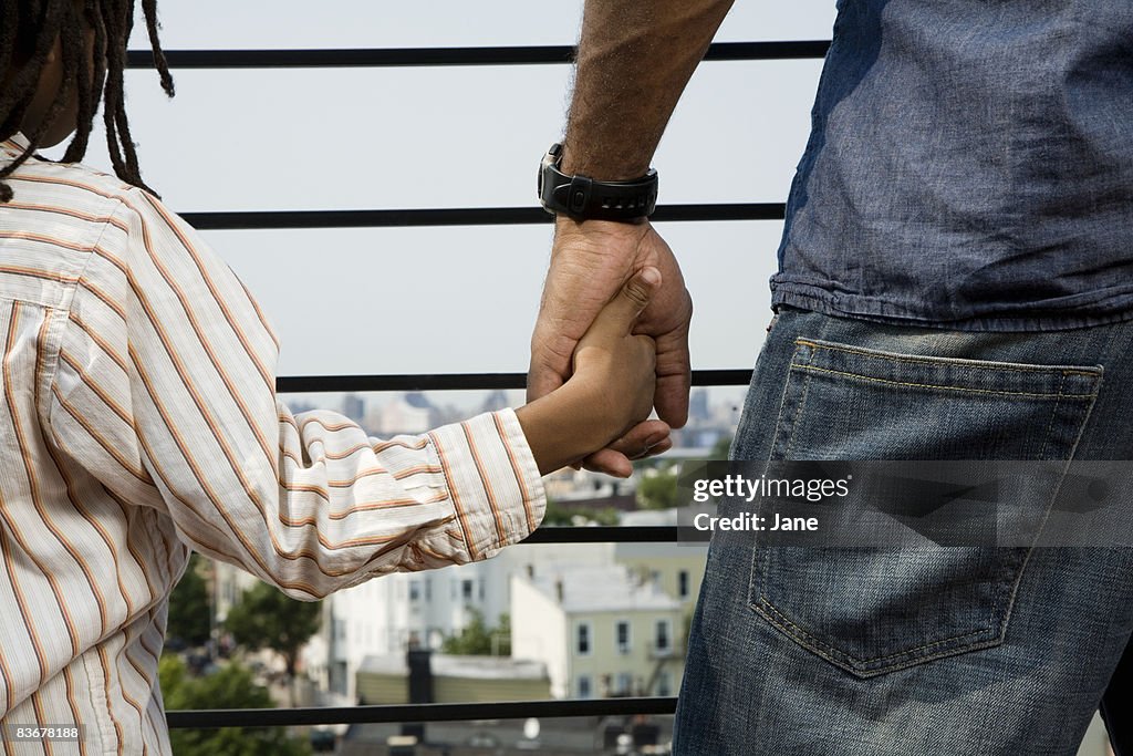 A father and son holding hands on a balcony