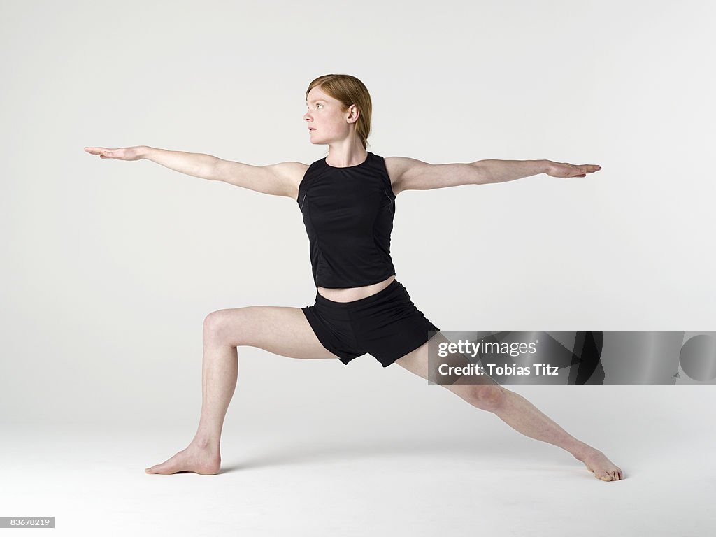 A young woman practicing the 'Warrior II' yoga pose