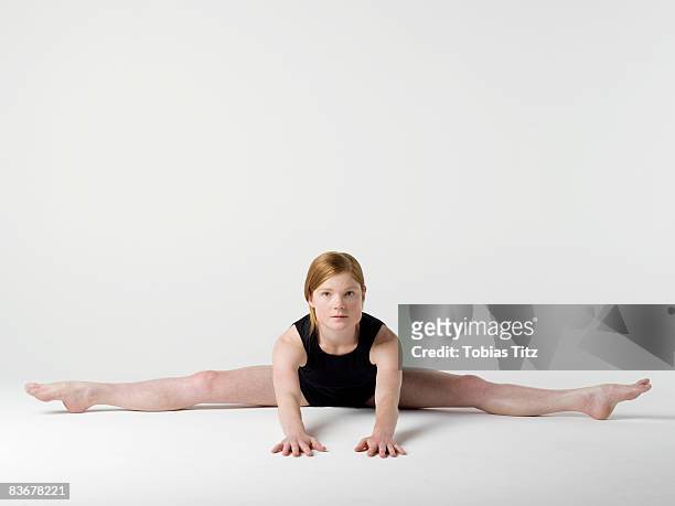 a young woman practicing the 'spread leg forward fold' yoga pose - woman leg spread stock pictures, royalty-free photos & images