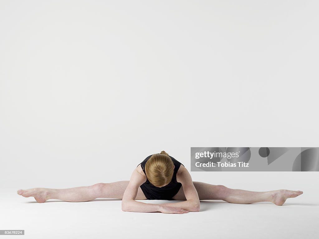 A young woman practicing the 'Spread Leg Forward Fold' yoga pose