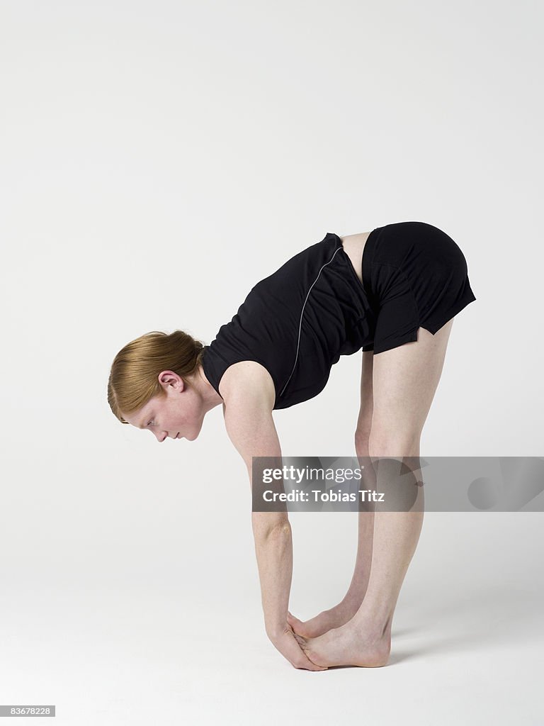 A young woman practicing the 'Upward Forward Fold' yoga pose