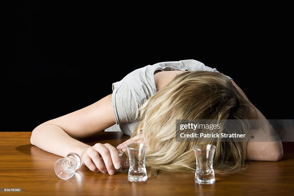 A young woman passed out drunk on a bar counter