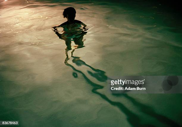a young woman standing in a swimming pool at night, silhouette - spooky night stock pictures, royalty-free photos & images