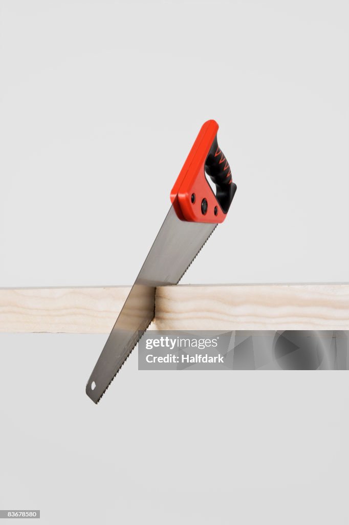 A saw cutting a plank of wood