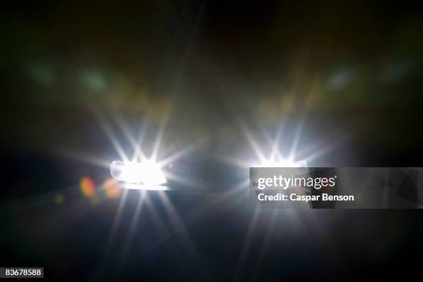 a car headlights illuminated at night - headlamp stock pictures, royalty-free photos & images