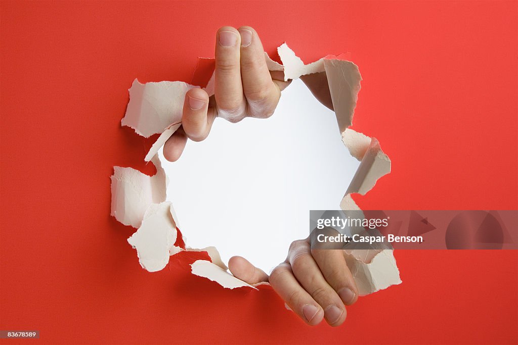 Hands breaking through a wall