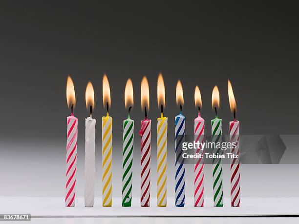 a row of burning multi colored birthday candles - candeline di compleanno foto e immagini stock
