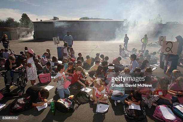 Students of Stevenson Elementary School are gathered in the playground as smoke rises from the simulated burning school auditorium during the...