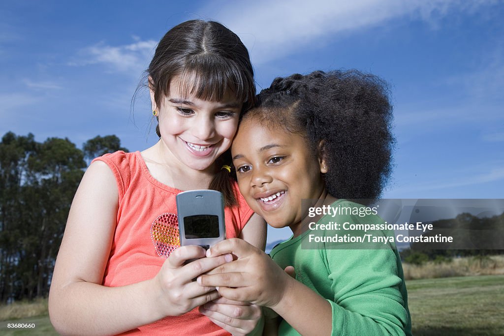 Two little girls on cell phone, smiling