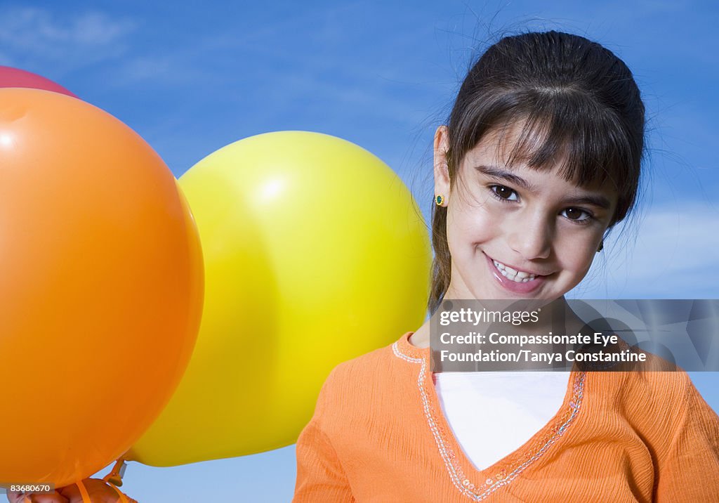 Little girl holding balloons, smiling
