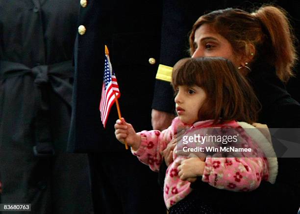 Two-year-old Angeli Greico waves an American flag while sitting on her mother Rashmi's lap during burial services for her father, Staff Sgt. Kevin D....