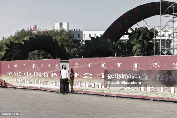 Women look behind a display wall in Baotou, Inner Mongolia, China, on Friday, Aug. 11, 2017. China's economy showed further signs of entering a...