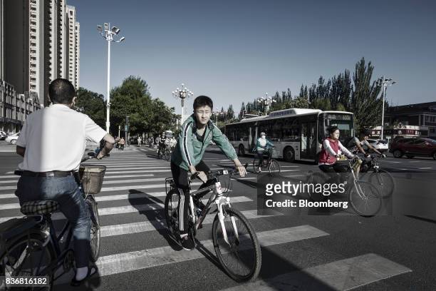 Commuters ride on bicycles down a main road in Baotou, Inner Mongolia, China, on Friday, Aug. 11, 2017. China's economy showed further signs of...