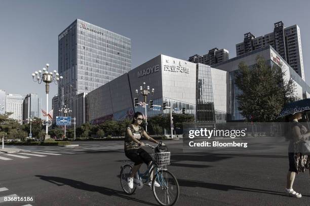 Woman rides a bicycle past a Maoye International Holdings Ltd. Department store in Baotou, Inner Mongolia, China, on Friday, Aug. 11, 2017. China's...