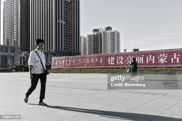 Woman walks through the main square in Baotou, Inner Mongolia, China, on Friday, Aug. 11, 2017. China's economy showed further signs of entering a...