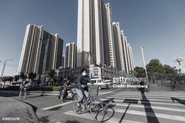 Commuters ride on bicycles past residential buildings in Baotou, Inner Mongolia, China, on Friday, Aug. 11, 2017. China's economy showed further...