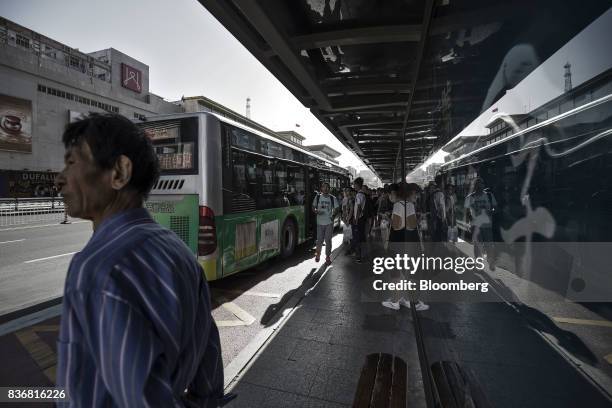 Commuters stand at a bus station in Baotou, Inner Mongolia, China, on Friday, Aug. 11, 2017. China's economy showed further signs of entering a...