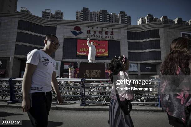 Pedestrians walk past a statue of Mao Zedong displayed in front of the Baotou Victory Shopping Mall in Baotou, Inner Mongolia, China, on Friday, Aug....