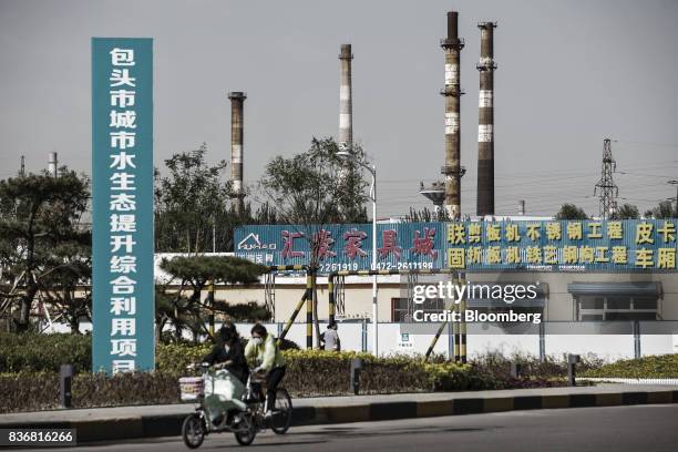 Commuters ride on bicycles past an industrial area in Baotou, Inner Mongolia, China, on Friday, Aug. 11, 2017. China's economy showed further signs...