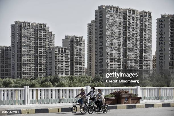 Commuters ride on bicycles past new residential buildings in Baotou, Inner Mongolia, China, on Friday, Aug. 11, 2017. China's economy showed further...