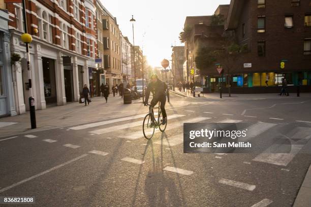 Male cyclists rides through Covent Garden on 10th January 2017 in London, United Kingdom. Sunset at the junction of Long Arce and Bow Street in...