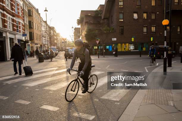 Male cyclists rides through Covent Garden on 10th January 2017 in London, United Kingdom. Sunset at the junction of Long Arce and Bow Street in...