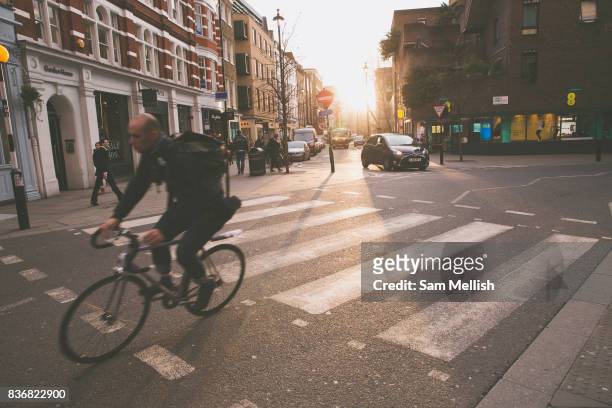 Male cyclists rides through Covent Garden on 10th January 2017 in London, United Kingdom. Sunset at the junction of Long Arce and Bow Street in...