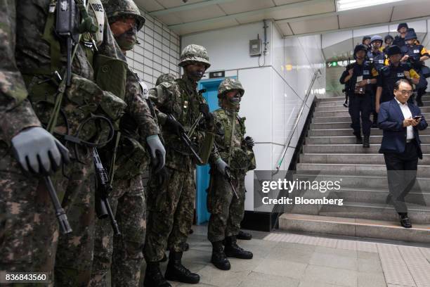 Bystander looks at his smartphone as soldiers stand guard during an anti-terror drill on the sidelines of the Ulchi Freedom Guardian military...