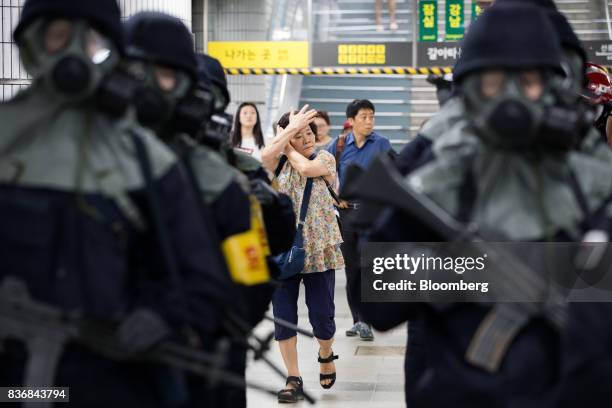 People walk past police officers wearing gas masks during a simulated chemical terrorism crisis as part of an anti-terror drill on the sidelines of...