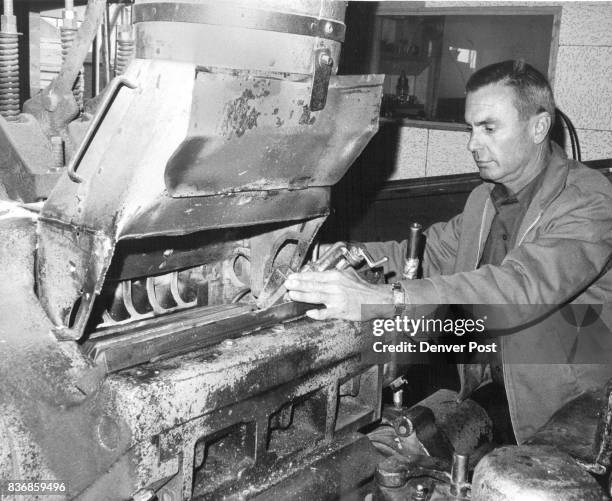 Byron Colter makes ad­justments on big planer at the Denver plant. The mass production equip­ment planes rough cut lumber down to finished...