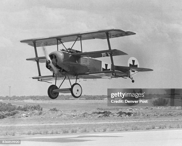 The Red Baron's Fokker DR-1 triplane climbs into the Colorado sky above Stapleton International Airport, its fiery red color scheme glistening is...