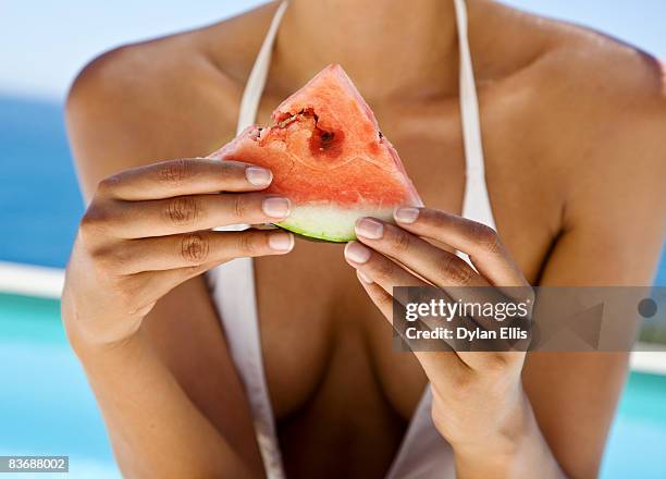 dark skinned woman eats fruit poolside. - swim suit stock pictures, royalty-free photos & images