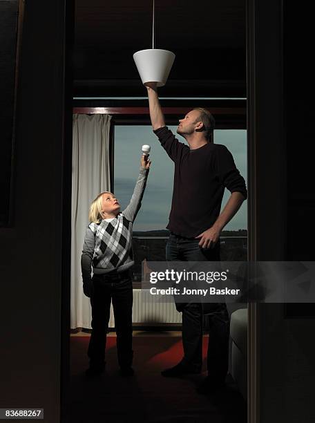 father and son changing bulb - posicionamiento fotografías e imágenes de stock
