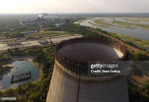 In this aerial view a partially-constructed and abandoned cooling tower stands as the new enclosure built over stricken reactor number four is seen...