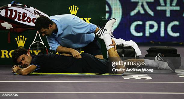 Roger Federer of Switzerland receives treatment from ATP trainer Hugo Gravil during his round robin match against Andy Murray of Great Britain in the...