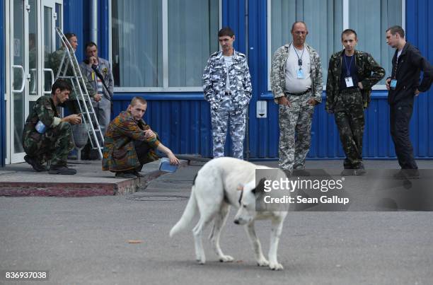 Workers on a break watch a stray dog saunter by outside an administrative building inside the exclusion zone at the Chernobyl nuclear power plant on...