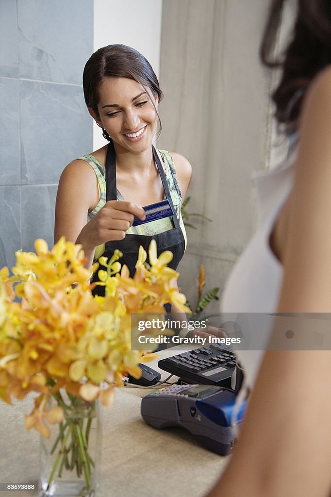 Female cashier looks at customer credit card 