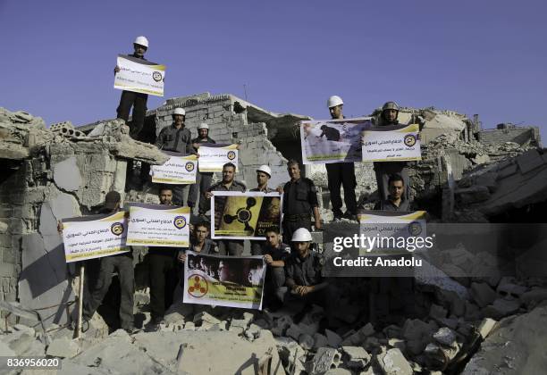 Men, members of Syrian civil defense organization, White Helmets hold a photo of a person and a placard who lost his life in chemical attack that in...