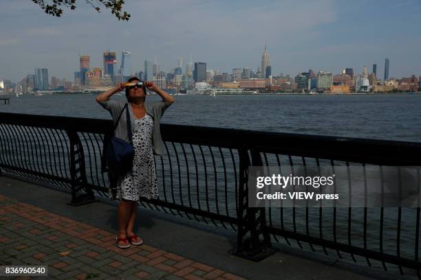 People watch the solar eclipse in front of the skyline of Manhattan as is seen from Hoboken, New Jersey on August 21,2017.