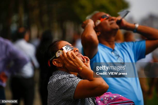 People watch the solar eclipse in front of the skyline of Manhattan as is seen from Hoboken, New Jersey on August 21,2017.
