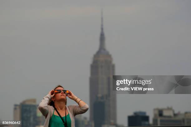 People watch the solar eclipse in front of the skyline of Manhattan as is seen from Hoboken, New Jersey on August 21,2017.