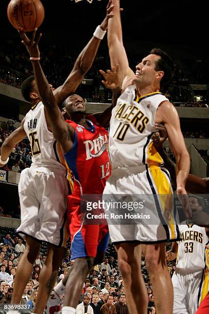 Royal Ivey of the Philadelphia 76ers drives against Jeff Foster and Brandon Rush of the Indiana Pacers at Conseco Fieldhouse on November 14, 2008 in...