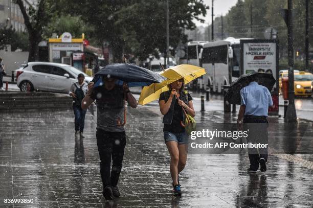 People walk with umbrellas on August 22, 2017 during a heavy rain at the Aksaray district in Istanbul. / AFP PHOTO / OZAN KOSE