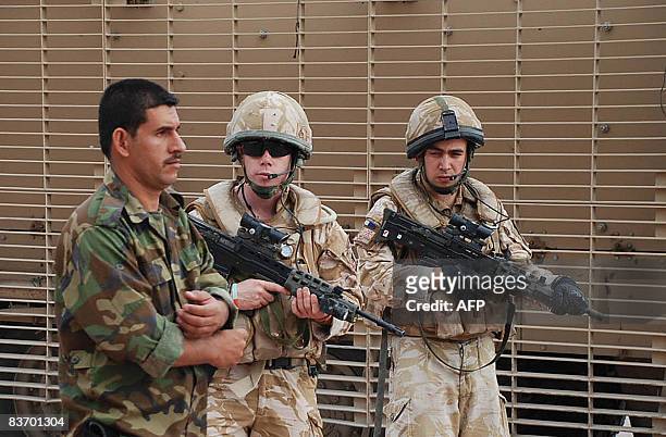 An Iraqi soldier walks past British soldiers on patrol in the southern city of Basra some 550 kms from the Iraqi capital Baghdad on November 13,...