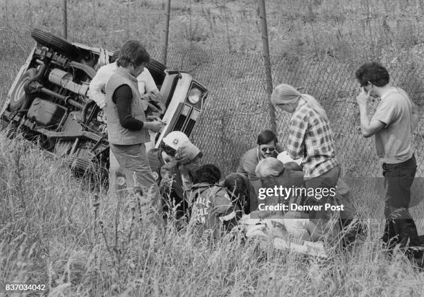 Members of the Idledale Fire Department and others aid a woman passenger injured when a pickup truck ran off Interstate 70 a half mile east of the...