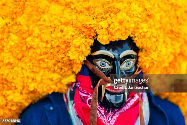 Mexican man, wearing a black wooden mask with marigold flowers, looks on during the Day of the Dead festivities on 29 October, 2016 in Mexico City,...