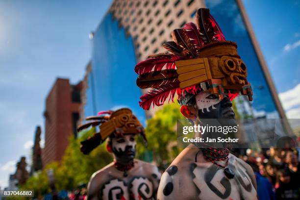 Mexican men, wearing colorful feather masks inspired by Aztecs, walk through the street during the Day of the Dead festival on October 29, 2016 in...