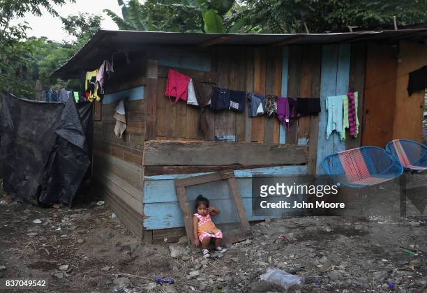 Child sits outside her family's one-room home in an impoverished neighborhood on August 19, 2017 in San Pedro Sula, Honduras. Honduras is...