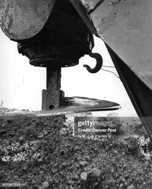 Construction worker Emary Adkins is almost obscured by dirt hurled out by drill which bores holes for the concrete caissons which will support the...